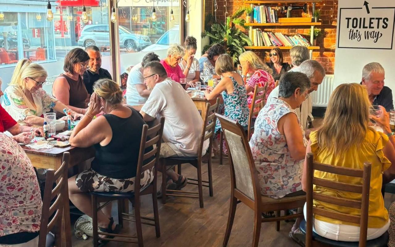 Groups of people sat round pub tables playing bingo